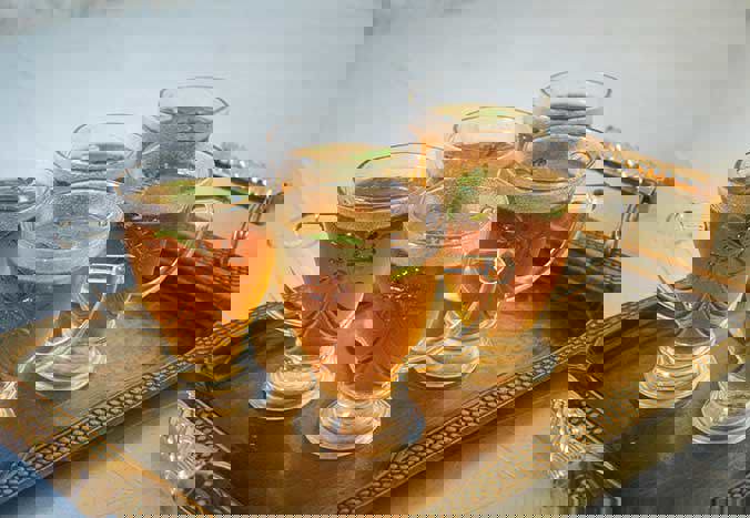 A tray of five ornate glass cups containing mint tea.